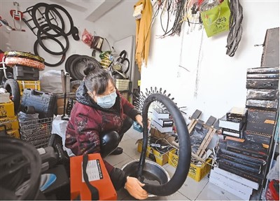 在天津市中新天津生态城第三社区中心，一家自行车修理店经营者正在检修轮胎 ... ...