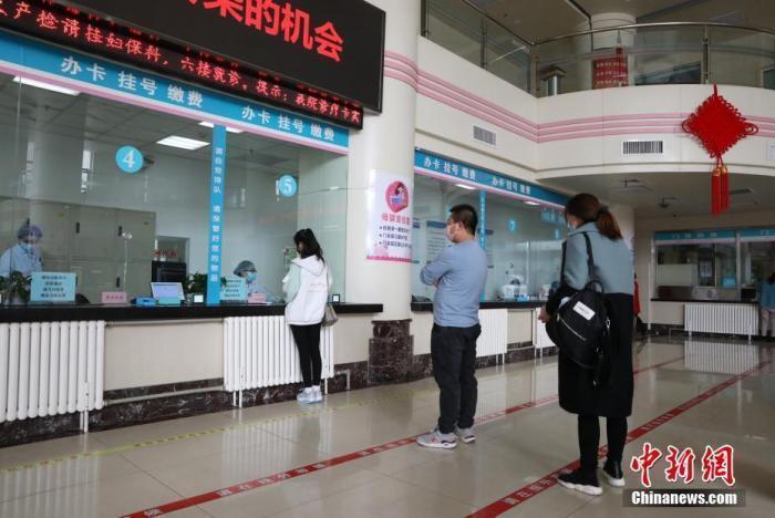 市民在医院门诊大厅间隔排队挂号