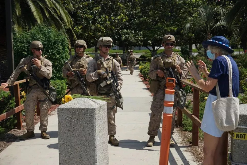 一名抗议者在美国洛杉矶威尔希尔联邦大楼旁与执勤的海军陆战队士兵交谈