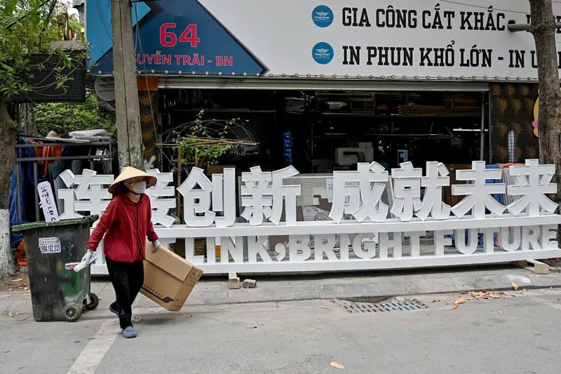 一名废品收集者走过北宁省一块中文招牌前